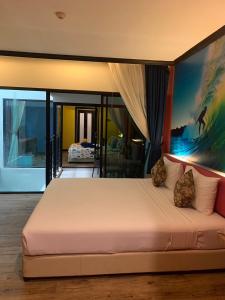 卡塔海滩Must Sea Hotel - SHA Hotel的卧室配有一张大床,墙上挂有绘画作品