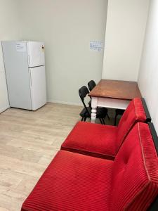 奥克兰Sky World Cozy Home的一张红色的沙发,位于一个配有桌子和冰箱的房间