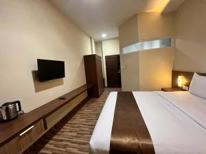 LubukpakamT HOTEL KUALANAMU的配有一张床和一台平面电视的酒店客房