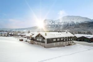 TorsetFossheim Lodge - komfortabel minileilighet的雪中的房子,背景是山