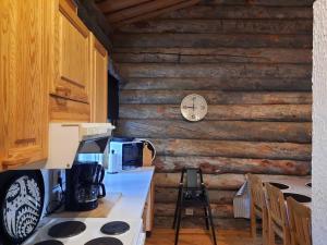 库萨莫Lumi - kelohirsimökki Rukalla, log cabin at Ruka的厨房配有炉灶和墙上的时钟