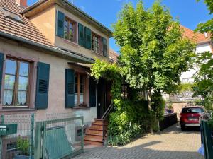 阿格诺Chez Rosa的一座有蓝色百叶窗的房子,前面有一棵树