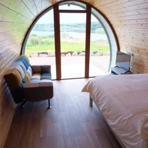 多尼戈尔Wheelhousepods glamping的一间卧室配有一张床、一张沙发和一个窗口