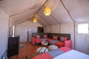 梅尔祖卡Golden Camp & Oasis的一间配有沙发的房间和一张位于帐篷内的床铺