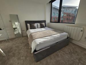 曼彻斯特Brand New Trafford Apartment的一间卧室设有一张大床和大窗户