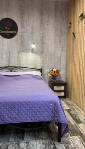 卡缅涅茨-波多利斯基Constancia的一间卧室配有紫色的床和鲜花桌