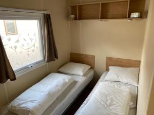 米德尔克尔克Stacaravan Middelkerke的小型客房 - 带2张床和窗户