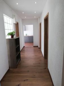 格拉芬韦赫尔Happy Apartment的走廊设有白色墙壁和木地板