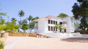 MaziziniThe Cliff 2 Bedroom Beach Apartment的一座棕榈树成荫的白色房子