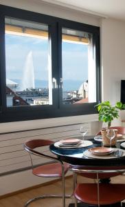 日内瓦WowAppartements vue sur le jet d'eau的一间带桌子和两把椅子的用餐室以及两扇窗户。