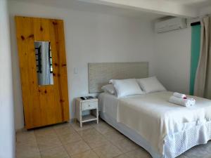 伊塔卡雷Itacaré Flats的卧室配有白色的床和小桌子