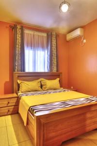 杜阿拉Meuble Modon Nyalla的一间卧室配有一张带黄色床单的床和一扇窗户。