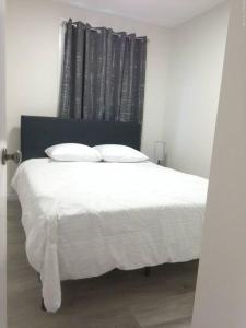 埃德蒙顿Sweethome - 10 min to Rogers Place & so much more的卧室内的一张带白色床单和枕头的床