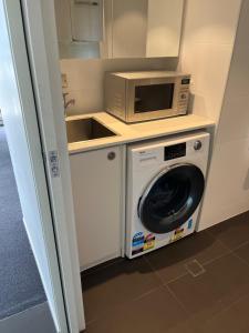 阿德莱德城市附近豪华公寓式酒店的厨房配有微波炉和洗衣机。