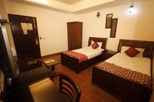 新德里Hotel Clark Height @New Delhi的小酒店客房设有两张床和一张桌子。