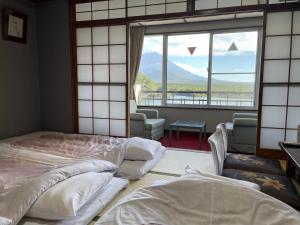 富士河口湖精进湖大酒店的带大窗户的客房内的两张床