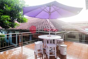 日惹Janna Guest House Syariah Yogyakarta Mitra RedDoorz的阳台上配有紫色雨伞的桌子