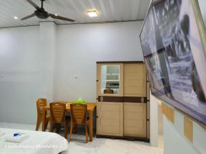 龙目岛库塔Lombokhouse Mandalika的一间带桌子和平面电视的用餐室