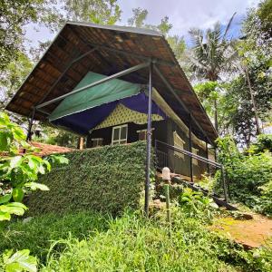 维特利Grassroots Wayanad, Valley-view Tents的森林中茅草屋顶的小房子