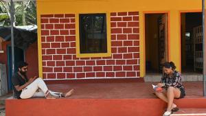 戈卡尔纳Trippr Gokarna - Beach Hostel的两个人坐在建筑物前面的路边