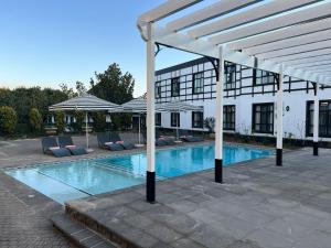 希尔顿ANEW Hotel Hilton Pietermaritzburg的一座带椅子的游泳池和一座白色的建筑
