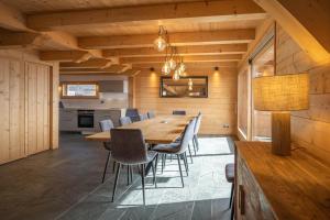 于埃Beau chalet GUSTAVE 4 chambres 50m piste Huez Express的一间带木桌和椅子的用餐室