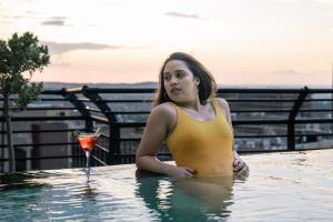 约翰内斯堡ANEW Hotel Parktonian Johannesburg的游泳池里的女人喝一杯