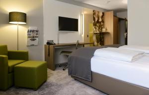 雷根斯堡ACHAT Hotel Regensburg im Park的酒店客房配有一张床、一张桌子和一把椅子。
