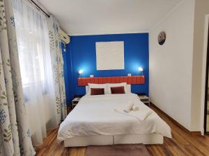 普洛耶什蒂Pensiunea & SPA Boema Ploiesti的蓝色的卧室设有白色的床和蓝色的墙壁