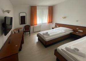韦特海姆Hotel am Malerwinkel的酒店客房设有两张床和电视。