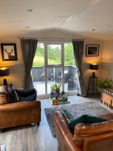 科弗Lovely new caravan by Loch Long的客厅设有两张沙发和一个大窗户