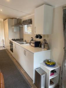 科弗Lovely new caravan by Loch Long的厨房配有白色橱柜和柜台上的一碗香蕉