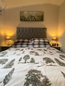 科弗Lovely new caravan by Loch Long的一间卧室配有一张床,床罩上布满了树木