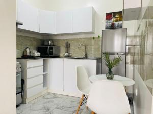 基加利White villa apartment的厨房配有白色橱柜和白色的桌椅