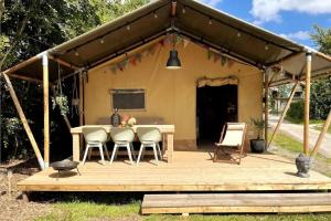 赫劳Glamping-tent 'Yatra Nirvana' met privé keuken en regendouche的木制甲板上的帐篷,配有桌椅