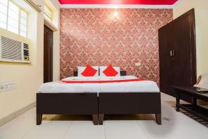 斋浦尔Collection O Hotel Rajwada Palace的一间卧室配有一张带红色枕头的床和一架钢琴