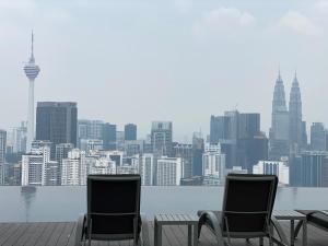 吉隆坡Lalaport Suites At Lucentia Bukit Bintang City Center的两把椅子坐在甲板上,享有城市美景