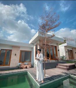库布盼洛坎Sari Sky Bali的站在游泳池旁房子前面的人
