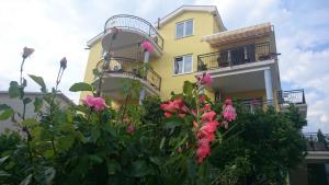 蒂瓦特Apartments Olga的前面有粉红色花的黄色房子