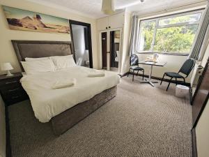 克劳利Little Foxes Hotel & Gatwick Airport Parking的一间卧室配有一张大床和一张桌子及椅子