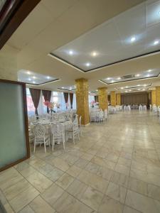 比斯特里察戴安娜酒店的宴会厅配有白色的桌椅和屏幕