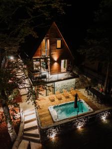 SoboliThe Magic Forest - Holiday Home & Spa Zone Platak的一个带椅子的游泳池,晚上有房子