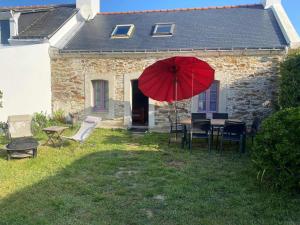 班戈Charmante maison en pierre avec jardin à Bangor, à 1500 m de la plage de Vazen - FR-1-418-157的房屋前的一张桌子和一把红伞