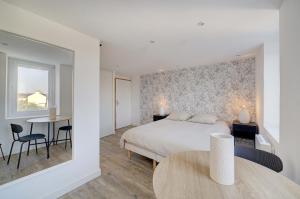 圣纳泽尔L'Espadon - Appart'Escale的卧室配有一张床和一张桌子及椅子