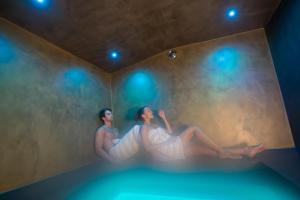 拉伊翁Hotel Weisses Rössl 3Sup的两个女人坐在一个有灯的房间的浴缸里