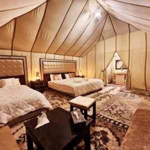 梅尔祖卡Sahara Luxury Glamping的一间卧室配有两张床,帐篷内配有一张桌子