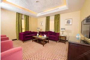 吉达Mercure Jeddah Al Hamraa Hotel的客厅配有紫色沙发和电视