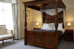 伯德利普Royal George Hotel by Greene King Inns的一间卧室配有一张天蓬床和一把椅子