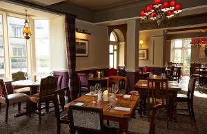 伯德利普Royal George Hotel by Greene King Inns的餐厅设有木桌、椅子和窗户。