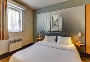 第戎B&B HOTEL Dijon Nord Zénith的卧室设有一张白色大床和两个窗户。